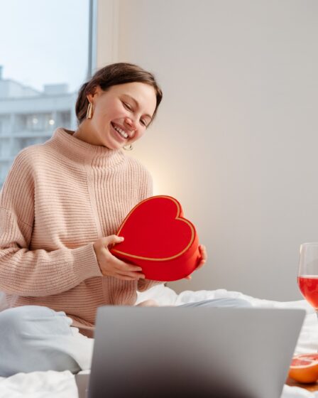 Woman holding gift box using laptop, online dating. Distance relationship, love, Valentine's Day